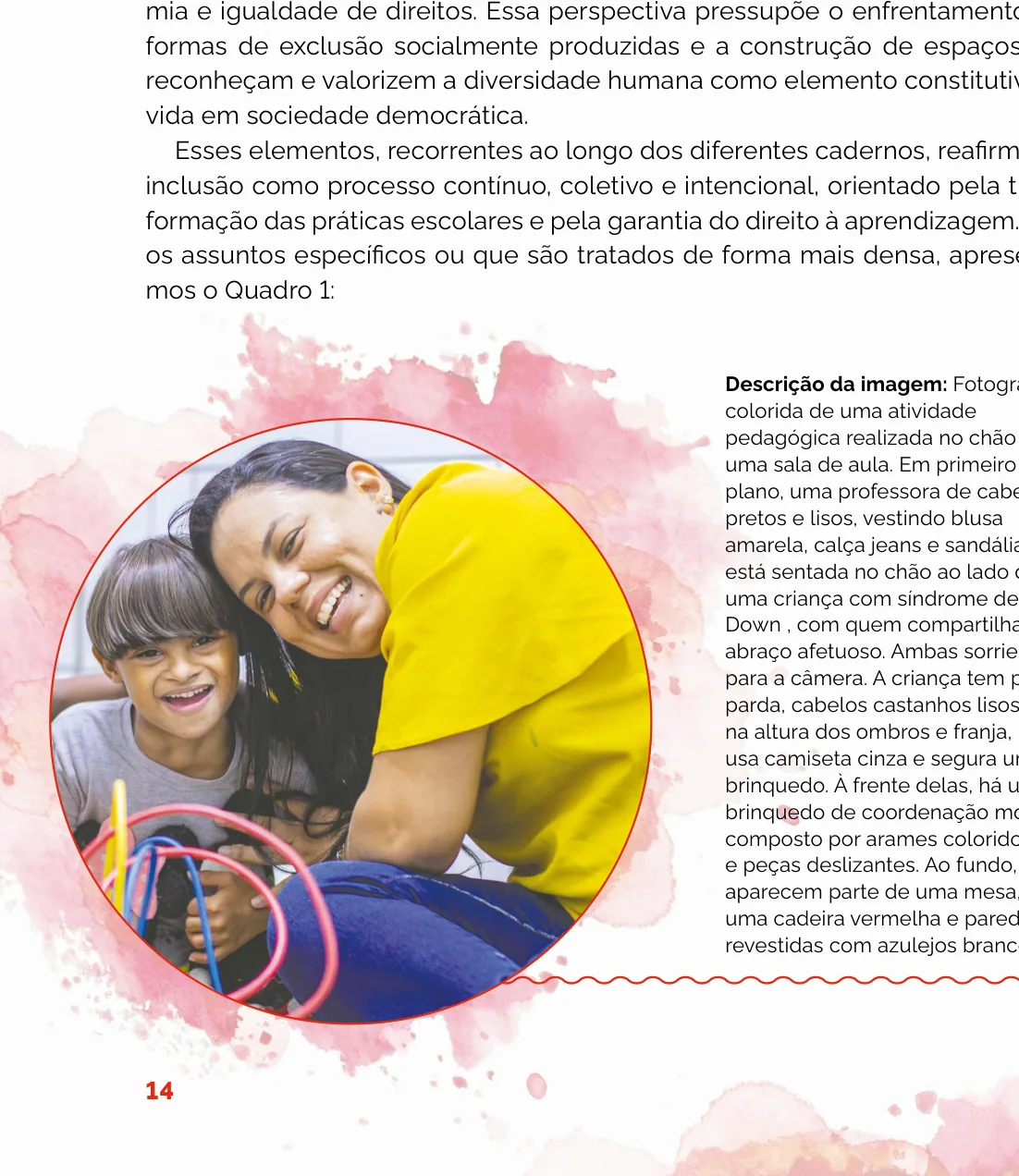 Fotografia de uma professora sentada no chão abraçando afetuosamente uma criança com síndrome de Down, ambas sorrindo, cercadas por um brinquedo de coordenação motora