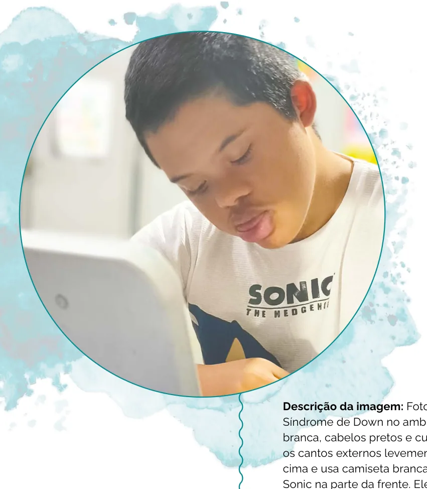 Fotografia de um estudante com Síndrome de Down concentrado em atividade escolar, segurando um lápis rosa sobre uma folha de papel