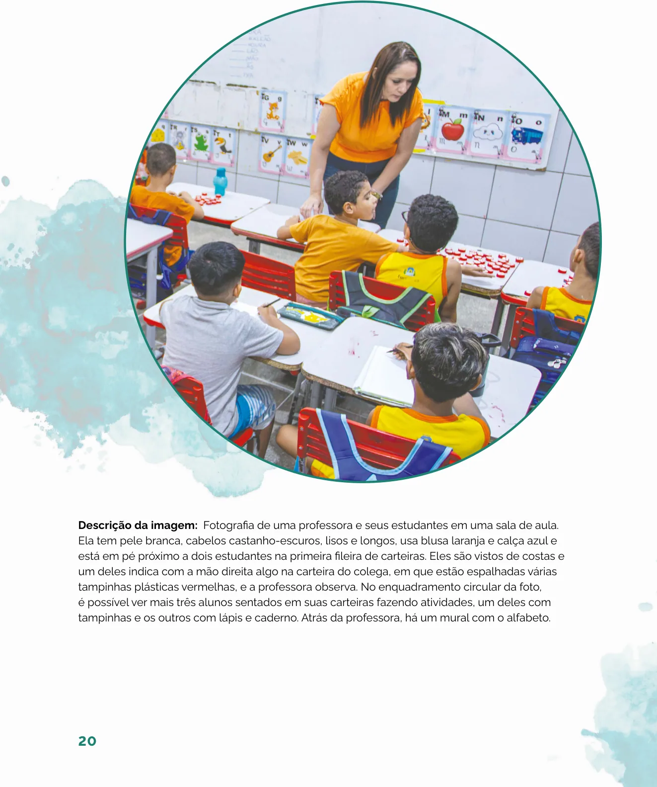Fotografia de uma professora ao lado de estudantes que realizam uma atividade com tampinhas plásticas na carteira, em uma sala de aula com mural de alfabeto ao fundo