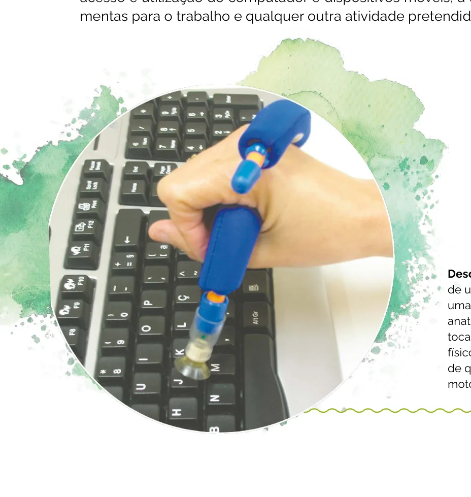 Fotografia de uma mão envolta por uma manopla de borracha anatômica, cuja ponteira única toca as teclas de um teclado físico