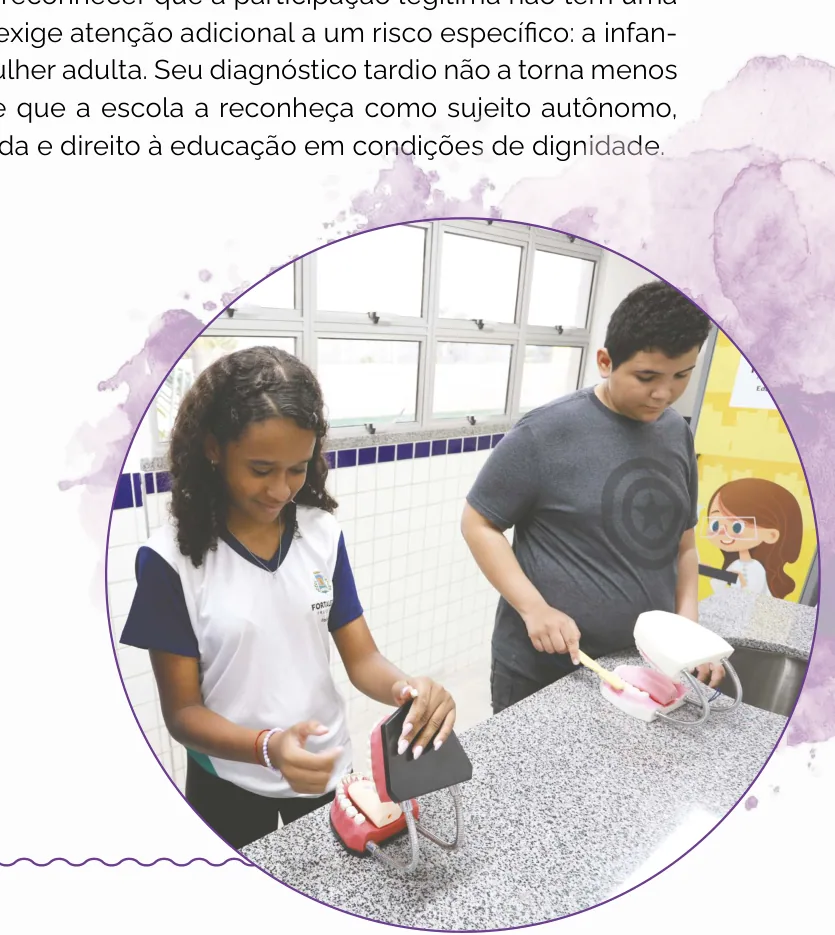Fotografia de dois estudantes manuseando modelos de arcada dentária sobre uma bancada, em atividade prática de higiene bucal