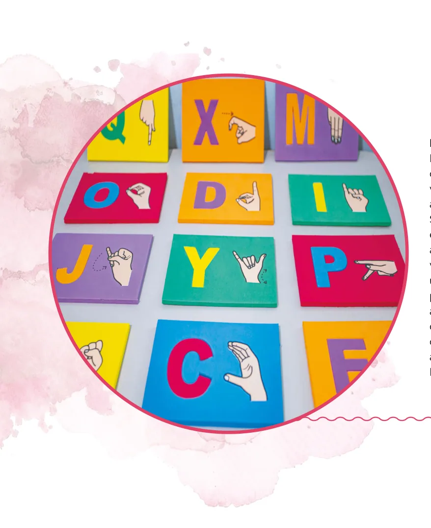 Fotografia de placas coloridas de material educativo para ensino do alfabeto e da Libras, cada uma com uma letra e a ilustração da mão fazendo o sinal correspondente